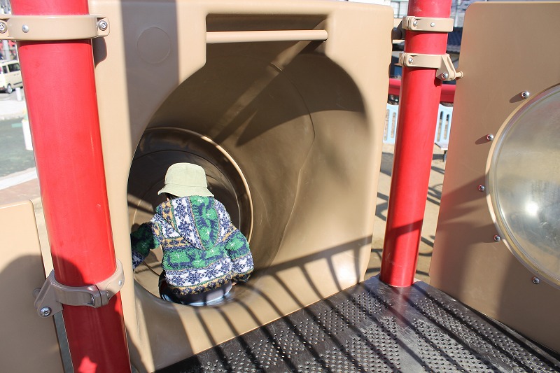 三本木公園のトンネル型の滑り台を滑る3歳児